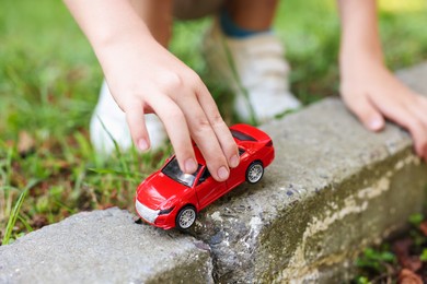 Photo of Little boy playing with toy car outdoors, closeup