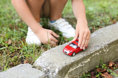Photo of Little boy playing with toy car outdoors, closeup