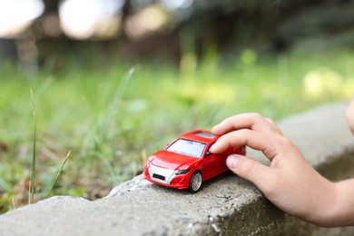 Photo of Little boy playing with toy car outdoors, closeup