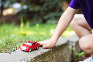 Photo of Little boy playing with toy car outdoors, closeup
