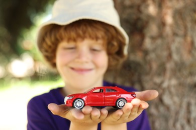 Photo of Little boy with toy car outdoors, selective focus