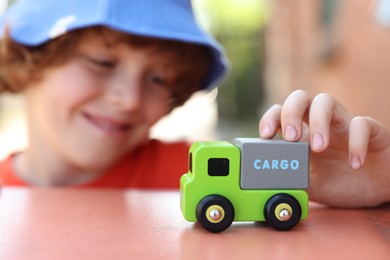 Photo of Little boy playing with toy car outdoors, selective focus