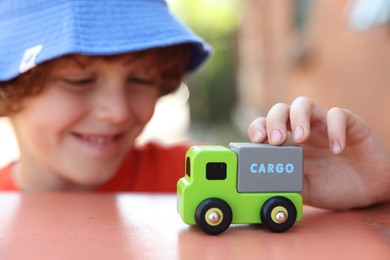 Photo of Little boy playing with toy car outdoors, selective focus