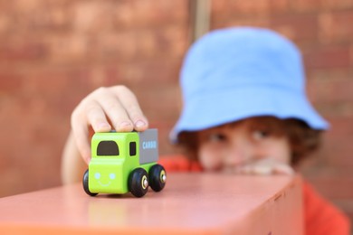 Photo of Little boy playing with toy car outdoors, selective focus