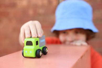 Photo of Little boy playing with toy car outdoors, selective focus