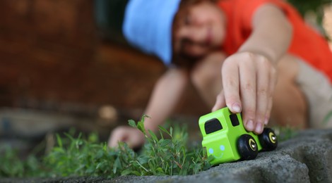 Photo of Little boy playing with toy car outdoors, selective focus