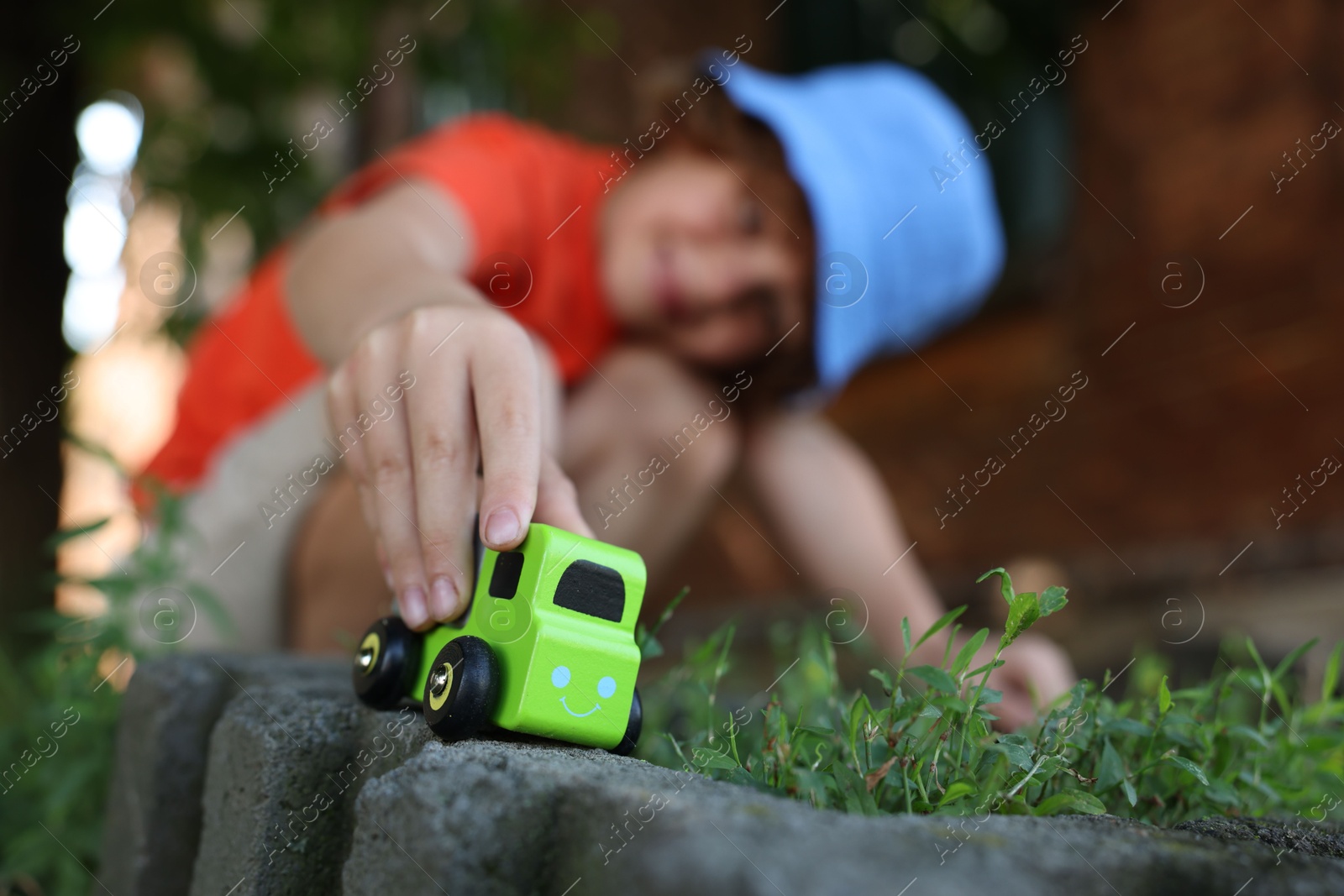 Little boy playing with toy car outdoors, selective focus Photo of Little boy playing with toy car outdoors, selective focus