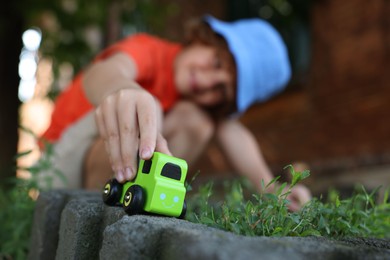 Photo of Little boy playing with toy car outdoors, selective focus