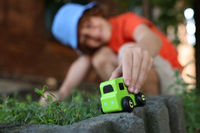 Photo of Little boy playing with toy car outdoors, selective focus