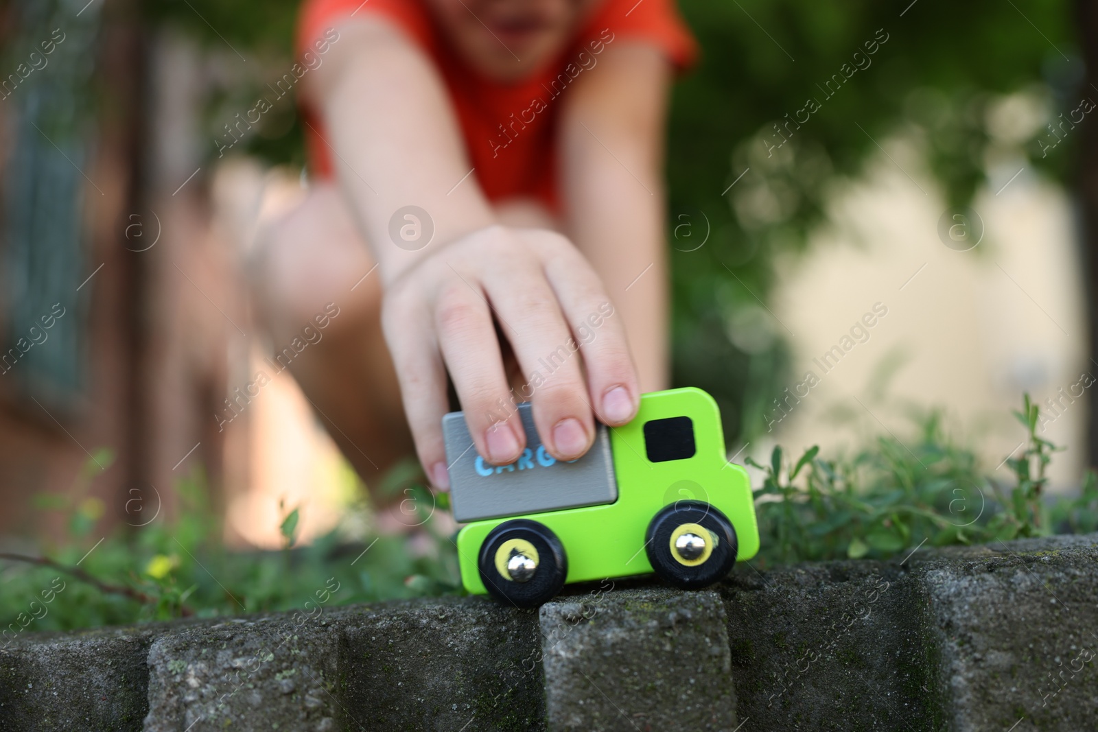 Photo of Little boy playing with toy car outdoors, closeup