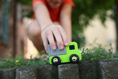 Photo of Little boy playing with toy car outdoors, closeup