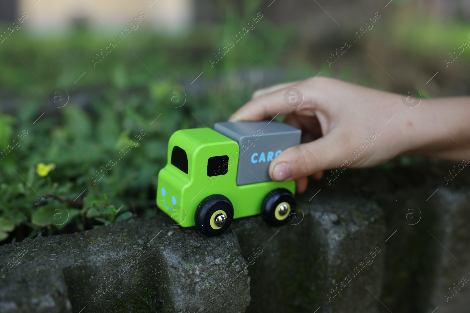 Photo of Little boy playing with toy car outdoors, closeup