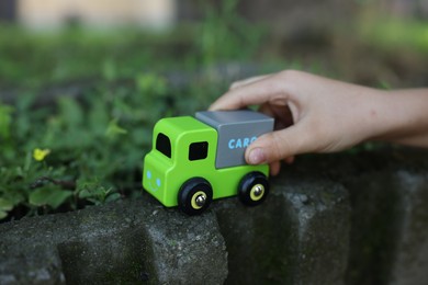 Photo of Little boy playing with toy car outdoors, closeup