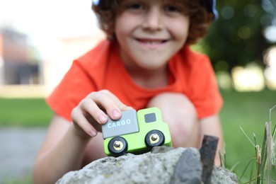 Photo of Little boy playing with toy car outdoors, selective focus