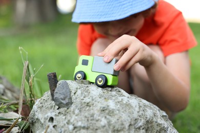 Photo of Little boy playing with toy car outdoors, closeup