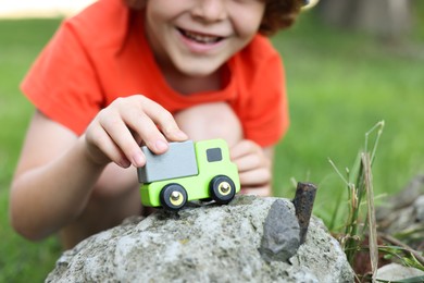 Photo of Little boy playing with toy car outdoors, closeup