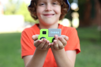 Photo of Little boy with toy car outdoors, selective focus