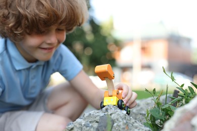 Photo of Little boy playing with toy car outdoors, selective focus