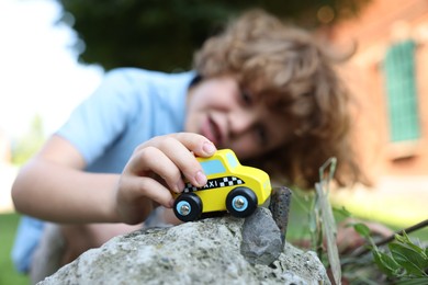 Photo of Little boy playing with toy car outdoors, selective focus