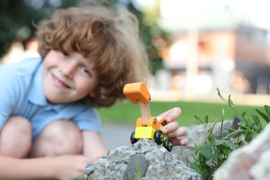 Photo of Little boy playing with toy car outdoors, selective focus