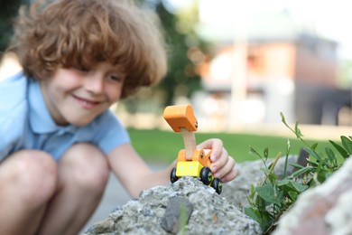 Photo of Little boy playing with toy car outdoors, selective focus