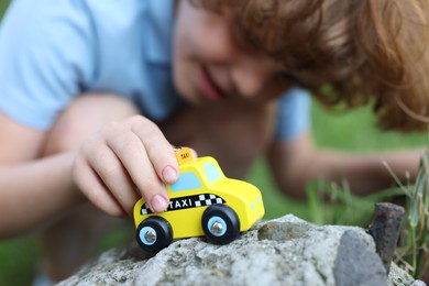 Photo of Little boy playing with toy car outdoors, selective focus