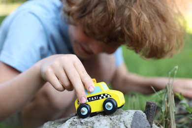 Photo of Little boy playing with toy car outdoors, selective focus