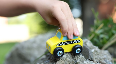 Photo of Little boy playing with toy car outdoors, closeup