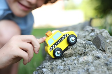 Photo of Little boy playing with toy car outdoors, closeup