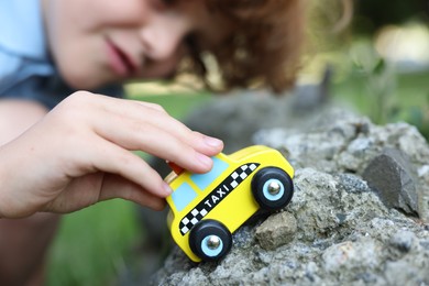 Photo of Little boy playing with toy car outdoors, selective focus