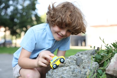 Photo of Little boy playing with toy car outdoors
