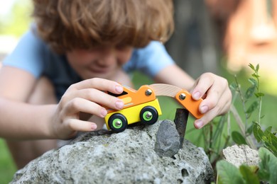 Photo of Little boy playing with toy car outdoors, selective focus