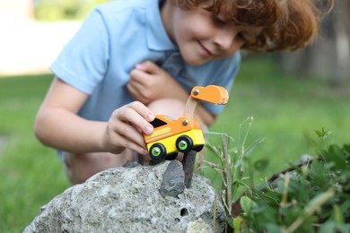 Photo of Little boy playing with toy car outdoors, selective focus