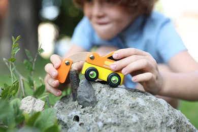Photo of Little boy playing with toy car outdoors, selective focus