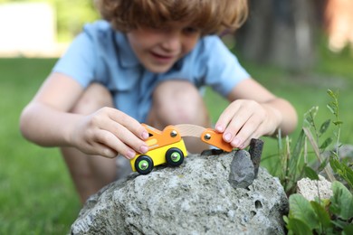 Photo of Little boy playing with toy car outdoors, selective focus