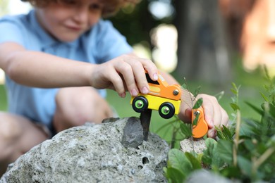 Photo of Little boy playing with toy car outdoors, selective focus