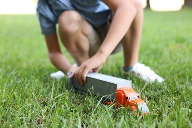 Photo of Little boy playing with toy car on grass outdoors, closeup