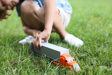 Photo of Little boy playing with toy car on grass outdoors, closeup