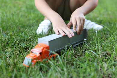 Photo of Little boy playing with toy car on grass outdoors, closeup