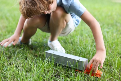 Photo of Little boy playing with toy car on grass outdoors, closeup