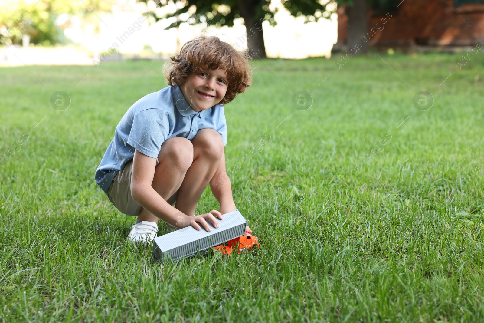Little boy playing with toy car on grass outdoors, space for text Photo of Little boy playing with toy car on grass outdoors, space for text