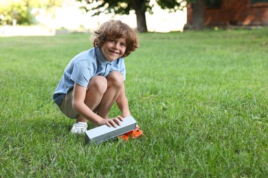 Photo of Little boy playing with toy car on grass outdoors, space for text