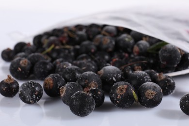 Photo of Ripe frozen black currants in open zipper bag on mirror surface against white background, closeup