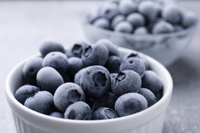 Photo of Ripe frozen blueberries in bowl on grey table, closeup