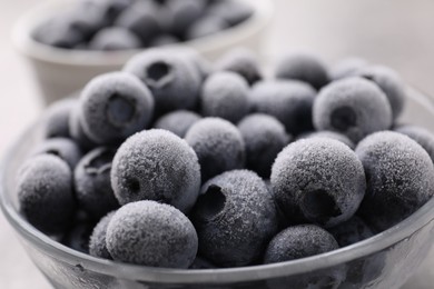 Photo of Ripe frozen blueberries in bowl on grey table, closeup