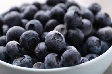Photo of Ripe frozen blueberries in bowl on grey table, closeup