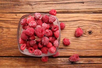 Photo of Ripe frozen raspberries in bowl on wooden table, flat lay
