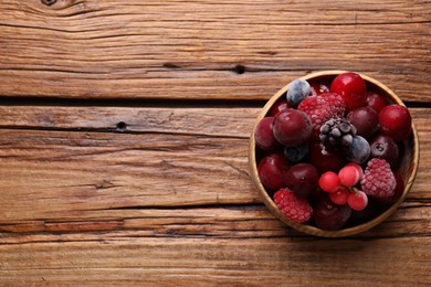Photo of Mix of ripe frozen berries in bowl on wooden table, top view. Space for text