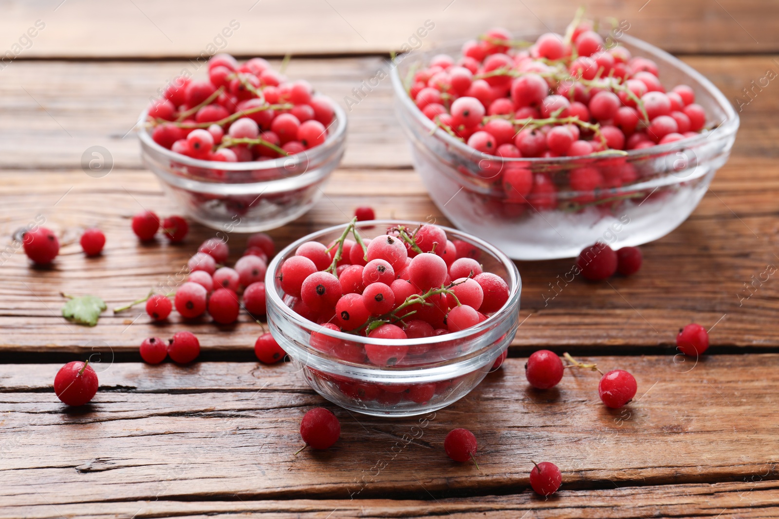 Photo of Ripe frozen red currants on wooden table, closeup