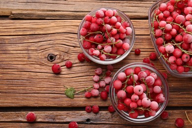 Photo of Ripe frozen red currants on wooden table, flat lay. Space for text